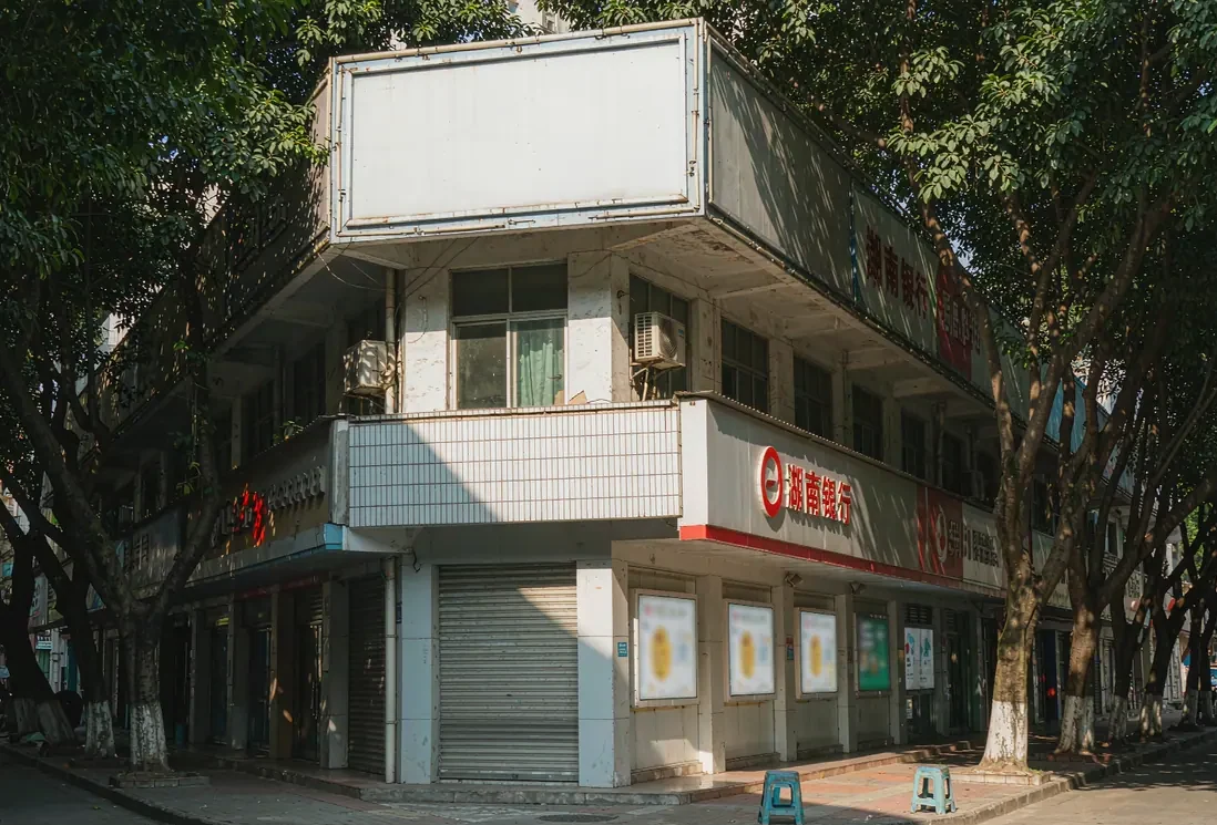 益阳街边商业楼外立面,楼顶大牌与临街门头招牌分层分布,午后晴光(AI生成示意图)